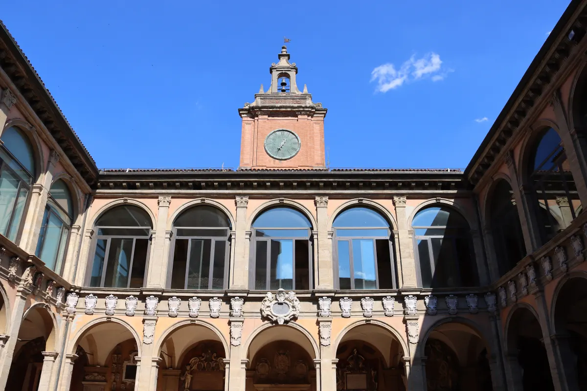 Cour à double galerie de l’Archiginnasio sous un ciel bleu, avec son petit campanile