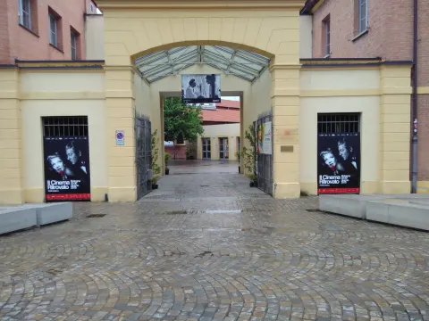 Entrée voûtée de la piazzetta Pasolini, avec des affiches de films