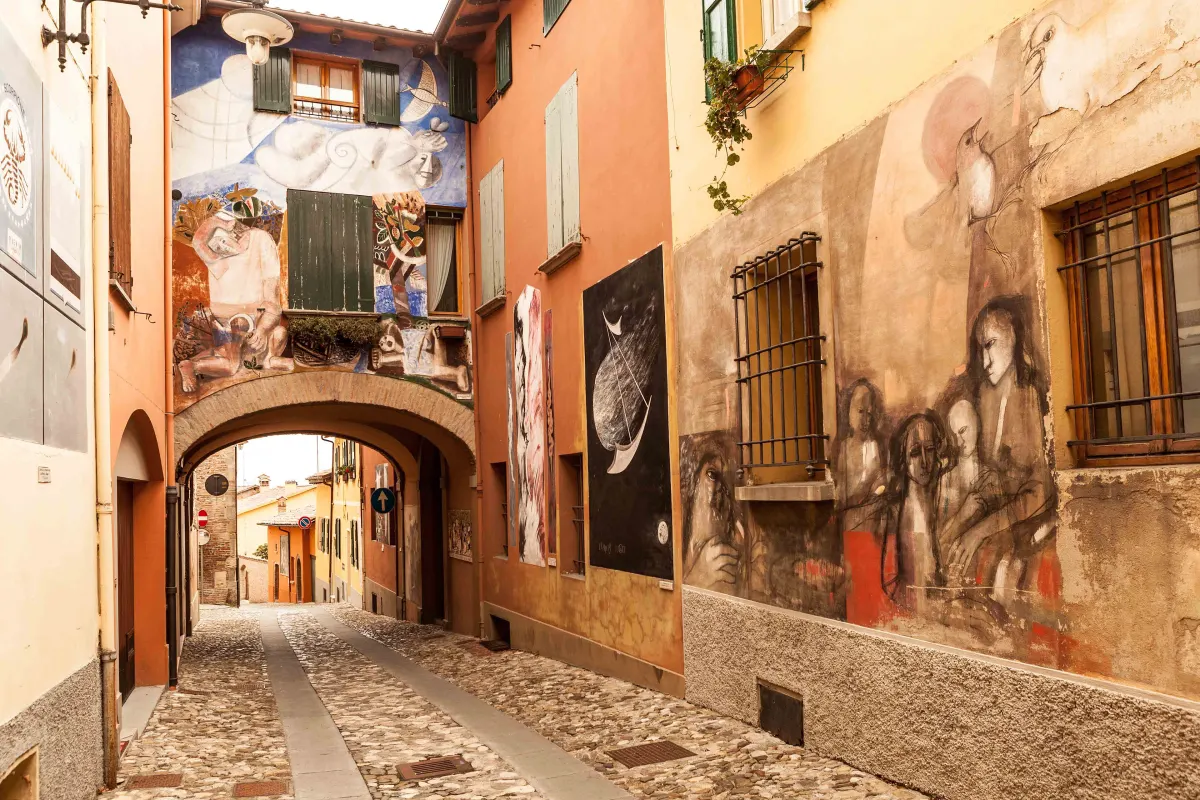Ruelle pavée de Dozza aux façades couvertes de peintures murales contemporaines
