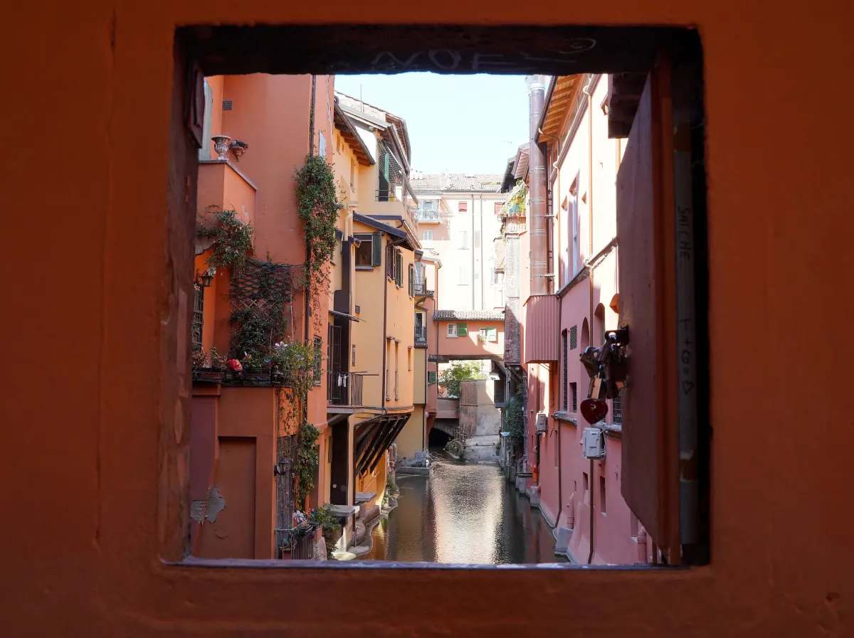 Petite fenêtre ouverte dans un mur de la via Piella donnant sur le canal delle Moline bordé de maisons colorées