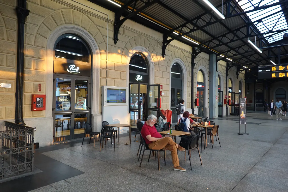 Quai historique de la gare Bologna Centrale avec sa marquise et une terrasse de café