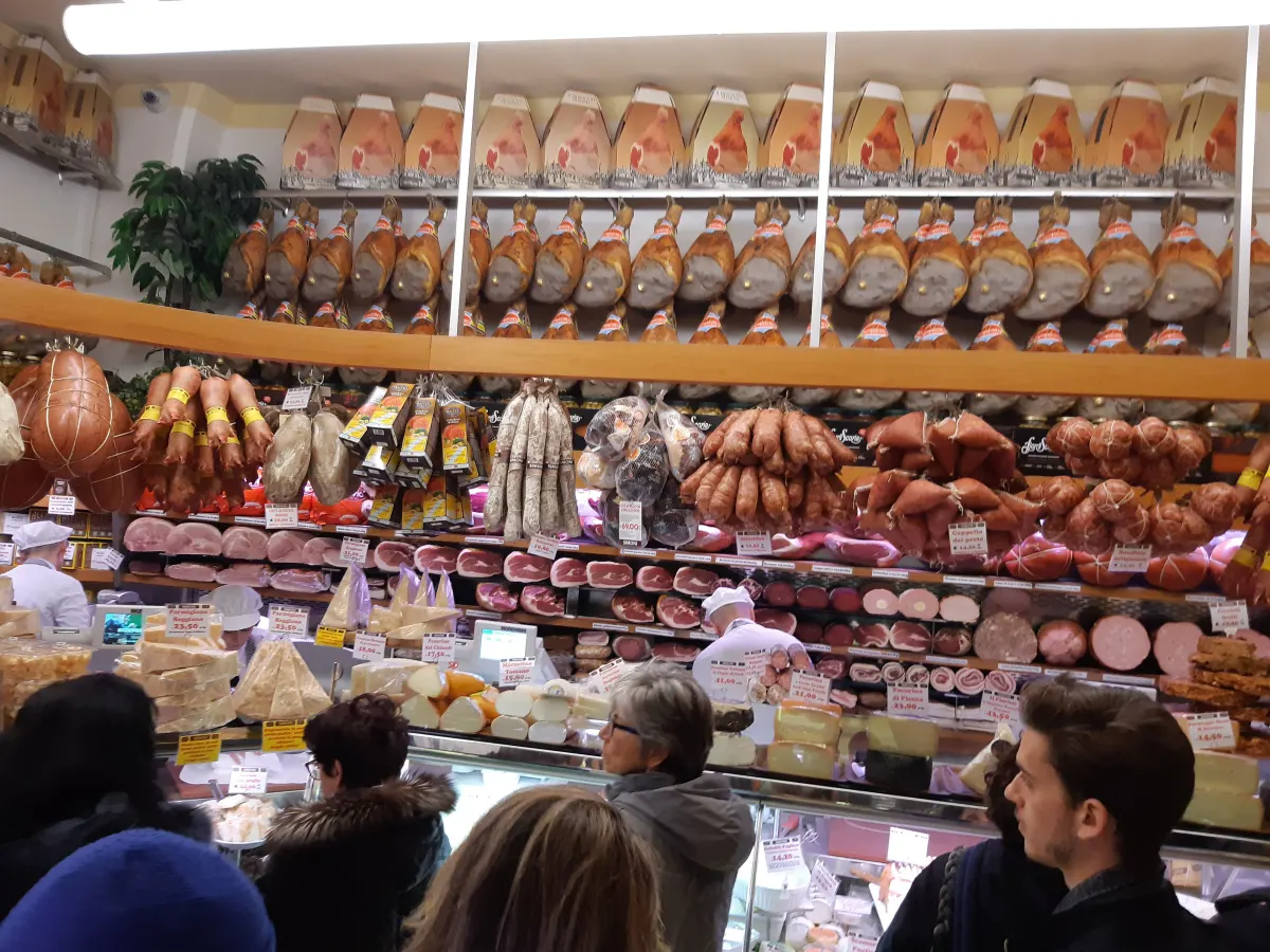 Jambons, saucisses et mortadelles suspendus en rangées dans une charcuterie de Bologne