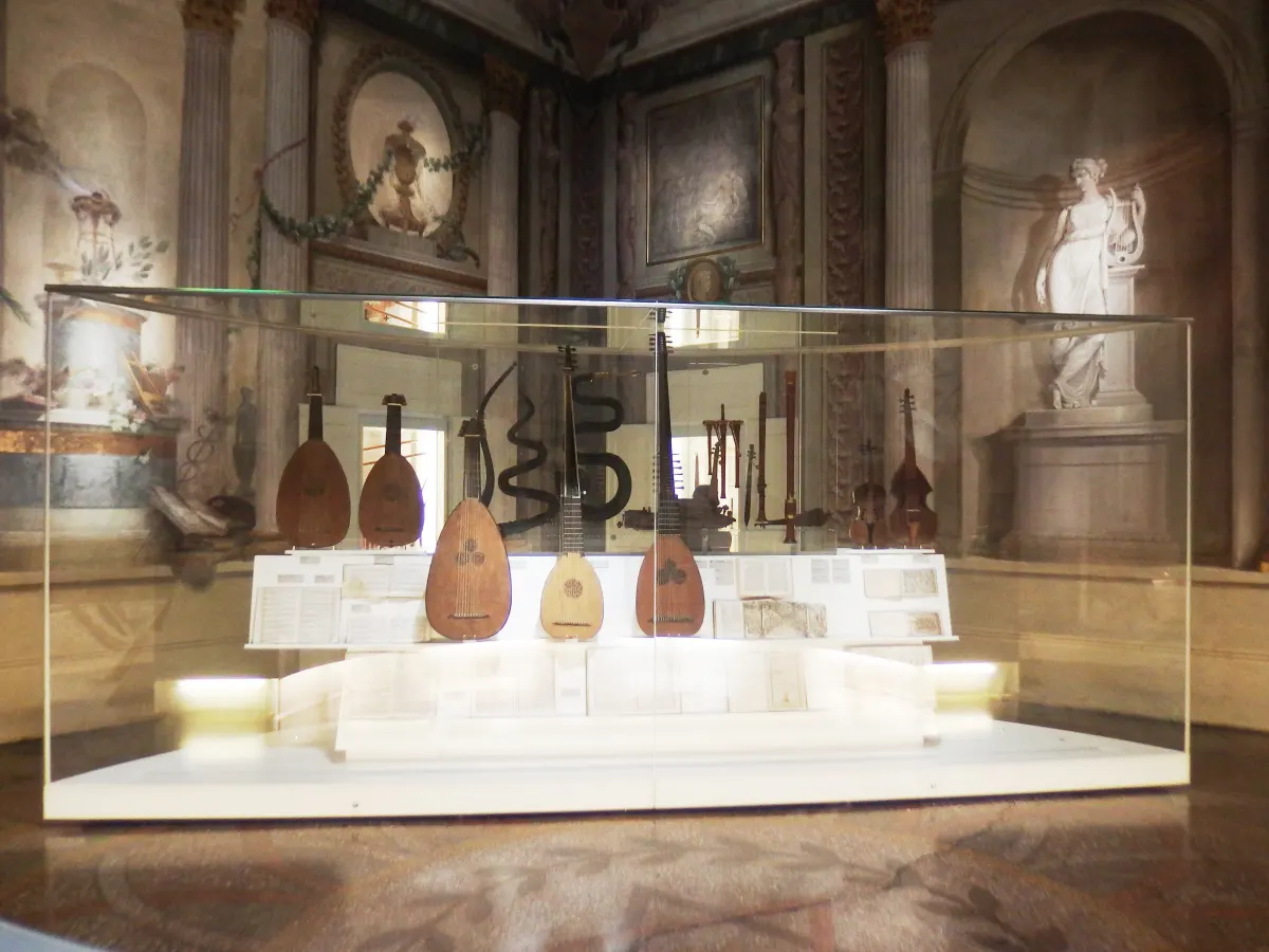 Vitrine d’instruments anciens, luths et guitares, dans une salle décorée du musée