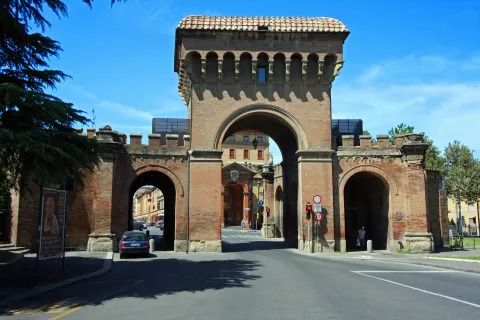 Porta Saragozza, porte crénelée en brique flanquée de deux tours, sous un ciel bleu