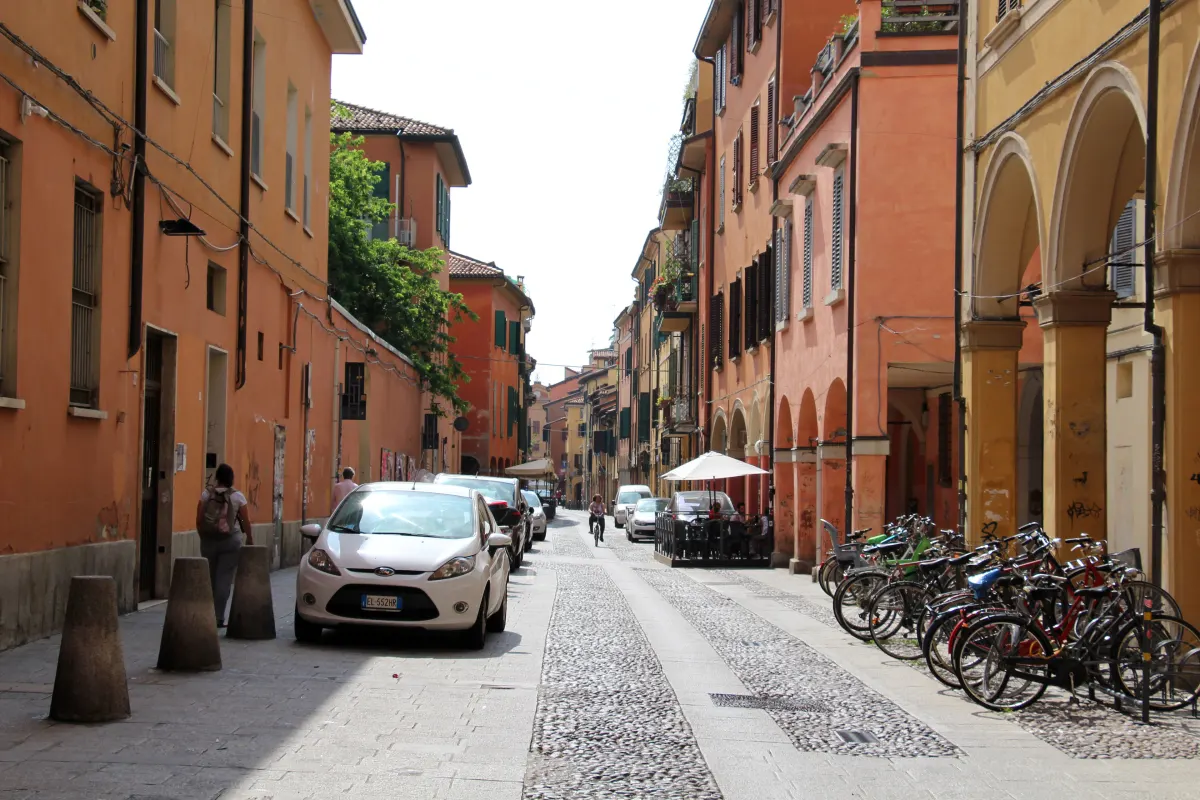 Rue pavée de la via del Pratello bordée de portiques et de façades colorées