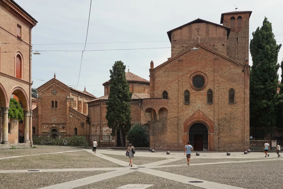 Façades en brique des églises du complexe de Santo Stefano sur la place triangulaire, entre cyprès