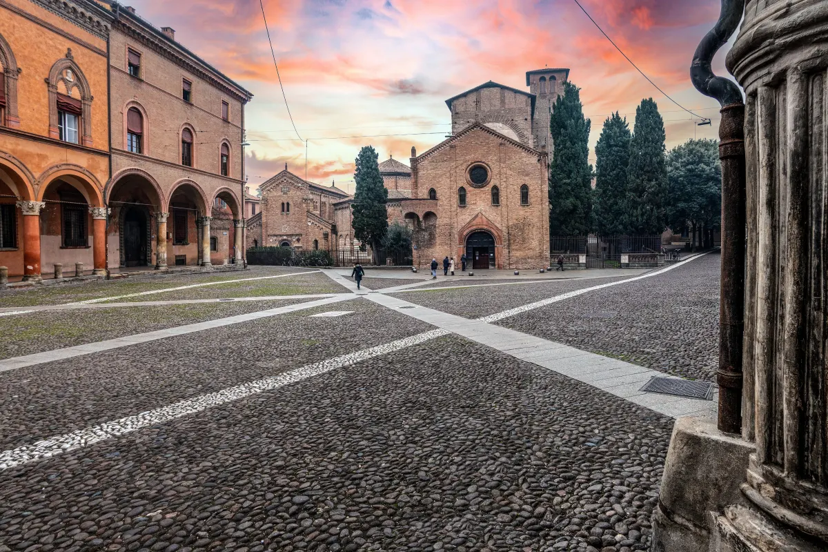 Piazza Santo Stefano au coucher du soleil, ciel rose au-dessus des églises et des portiques