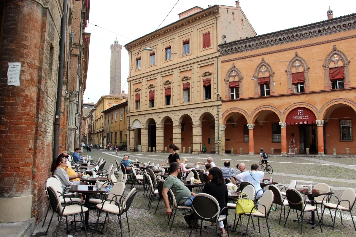 Palais à portiques et terrasses de café sur la piazza Santo Stefano, la tour des Asinelli au loin